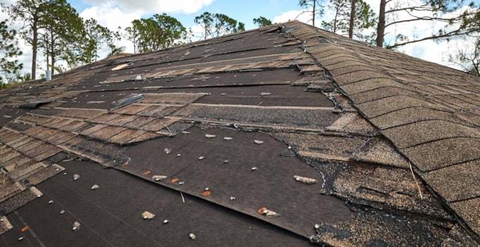 wind-damaged-house-roof-with-missing-asphalt-shingles-after-hurricane-ian-florida-repair-home-rooftop-concept