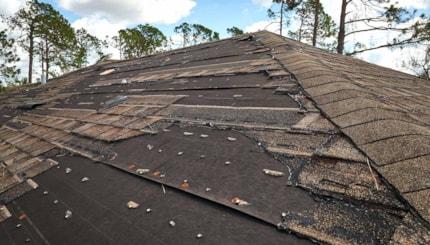wind-damaged-house-roof-with-missing-asphalt-shingles-after-hurricane-ian-florida-repair-home-rooftop-concept