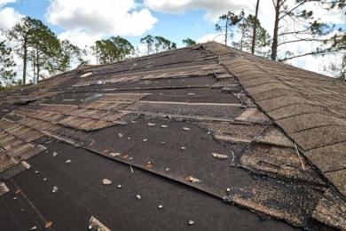 wind-damaged-house-roof-with-missing-asphalt-shingles-after-hurricane-ian-florida-repair-home-rooftop-concept