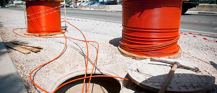 Fiber-optic cables are placed in a hole in preparation for an upcoming internet