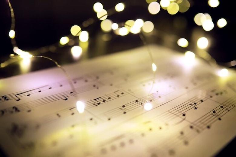 old-sheet-with-christmas-music-notes-as-background-against-blurred-lights-christmas-music-concept_494741-1310