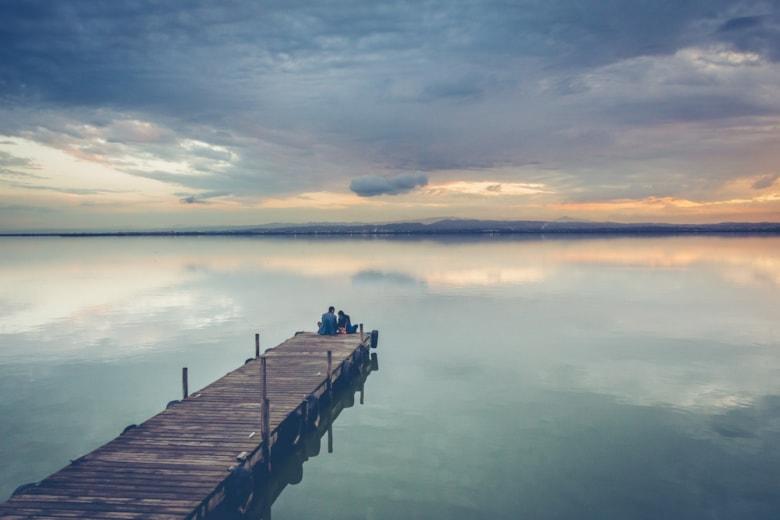 beautiful-couple-sitting-wooden-dock-beautiful-sunset-sky