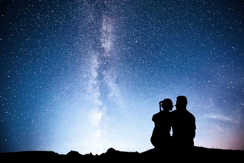 standing-man-woman-mountain-with-star-light-hugging-couple-against-purple-milky-way