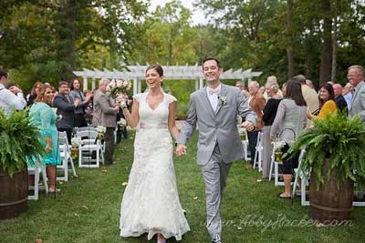 Mr. and Mrs. walking down the aisle at their outdoor wedding ceremony at The Lakefront Garden at The Willows