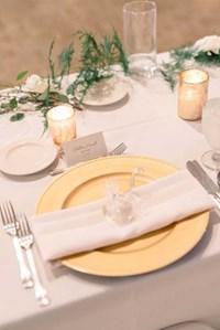 A place setting featuring white with gold accents for a wedding reception at The Willows Event Center