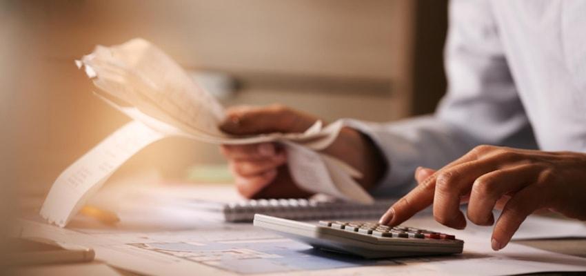 closeup-economist-using-calculator-while-going-through-bills-taxes-office closeup-economist-using-calculator-while-going-through-bills-taxes-office