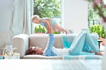 Mother holding her baby in the air in a new cleaned family room by Accent Maid Service in Indianapolis