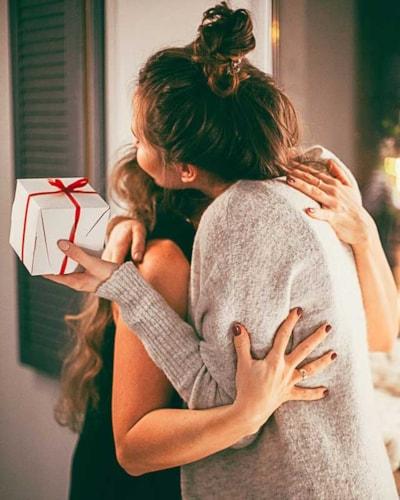 Women exchanging gifts and hugging