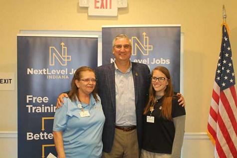 Indiana Governor, Eric Holcomb, in front of banners with NextLevel Jobs