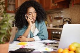 Woman on phone to workers comp attorney with medical bills from work inury in front of her (source: Freepik.com)