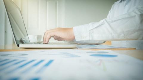businessman-analyzing-graphs-using-laptop-desk