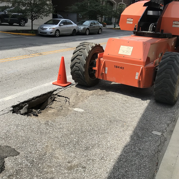 CH-Aerial lift In downtown Indy on city street.  Lift has enough weight to punch a hole in the pavement showing not all streets (and parking