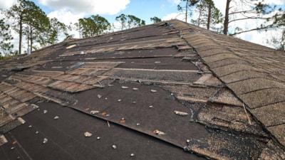 wind-damaged-house-roof-with-missing-asphalt-shingles-after-hurricane-ian-florida-repair-home-rooftop-concept