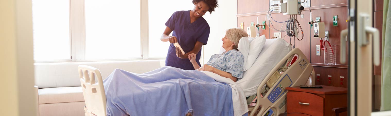 Doctor With Digital Tablet Talks To Patient