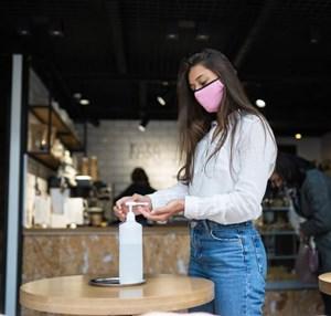Woman using sanitizer at a cafe to prevent spread of coronavirus (source: freepik.com)