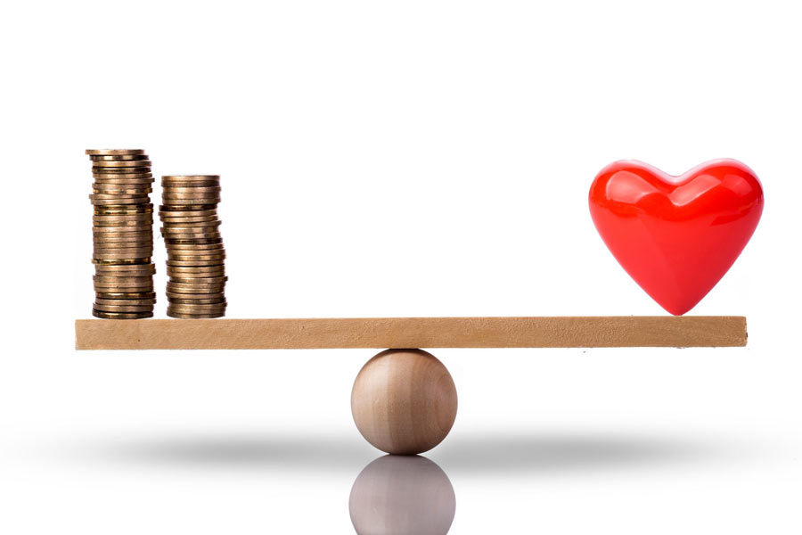 Heart and money (in coins) on a scale to represent balance