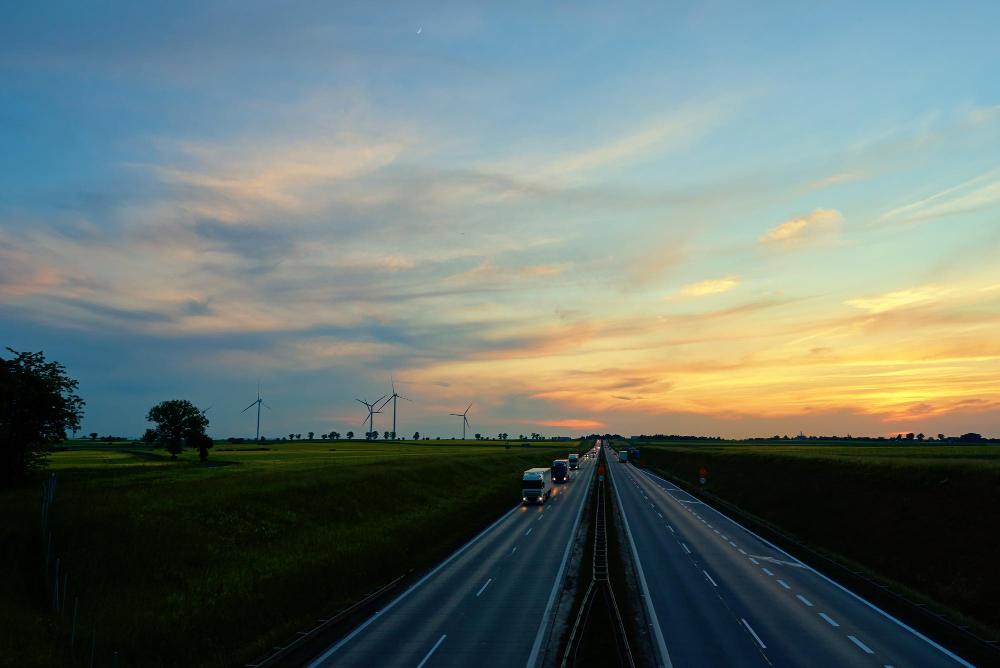 highway-road-with-car-traffic-windmill-turbine-generator-against-sunset-sky-concept-clean-ren