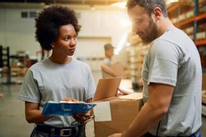 african-american-warehouse-worker-talking-her-colleague-while-working-industrial-storage-compartment